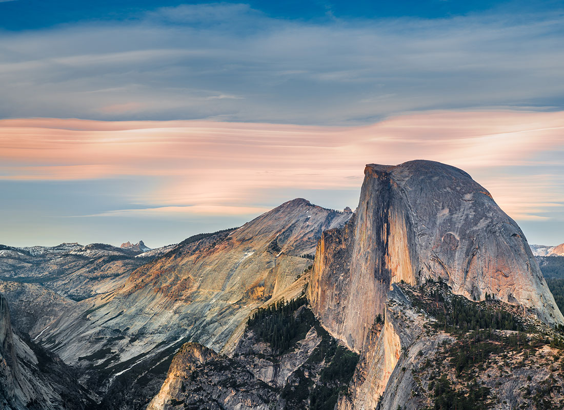 About Our Agency - Aerial View of Rocky Mountains in California Against a Colorful Cloudy Sunset Sky